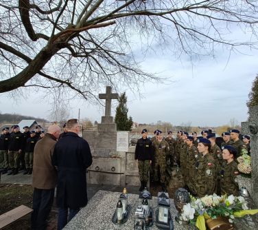 Cmentarz. Pomiędzy grobami grupa młodych żołnierzy w mundurach i niebieskich beretach. Po środku dwóch mężczyzn